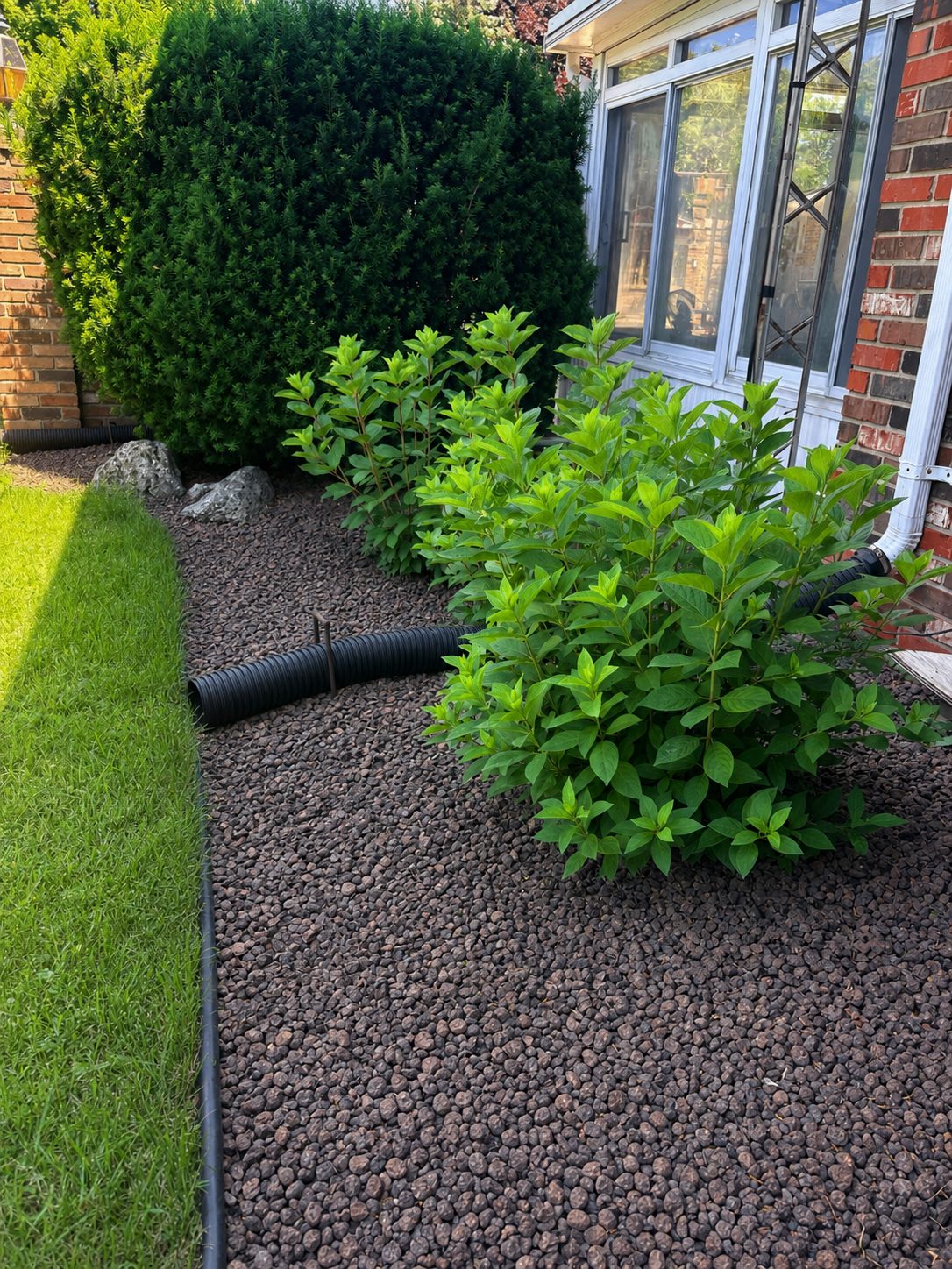 Freshly finished flower bed with dark decorative stone, shrubs and crisp edging